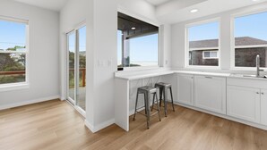 Una cucina moderna con mobili bianchi, un'ampia finestra e una porta scorrevole in vetro.