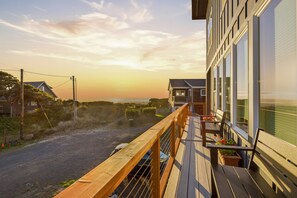 A wooden deck with a railing overlooking a road and a building with large windows. - Sea View-Brand new! Steps to beach, great views, open & spacious. (Cloverdale)