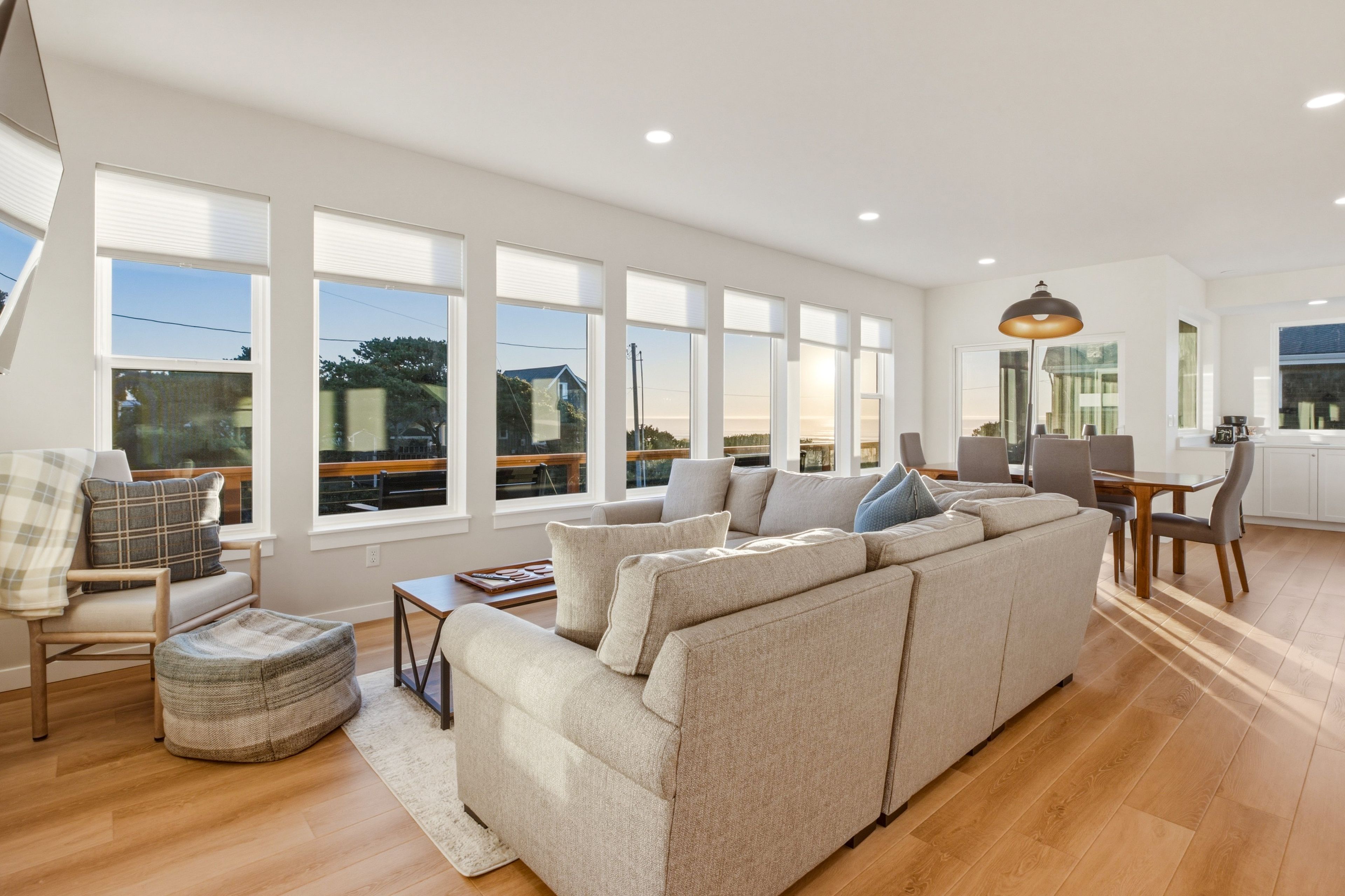 A spacious living area with a large sectional sofa, a dining table with chairs, and a kitchen area.