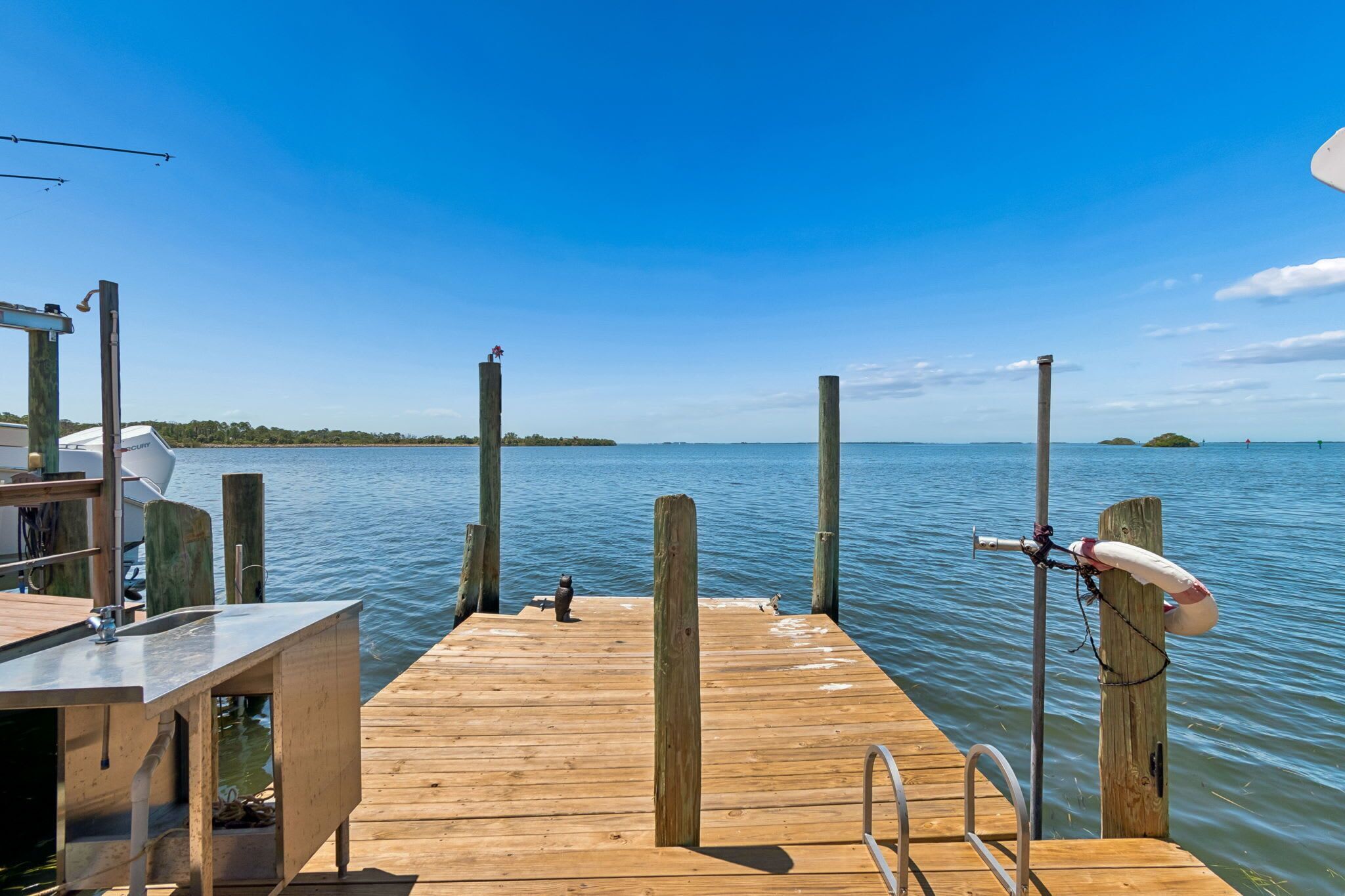 A wooden dock extending into calm water with a clear sky.