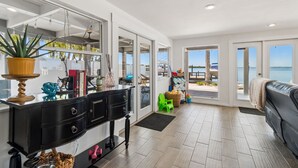 A modern interior with a dining area, a sofa, and a view of the sea.