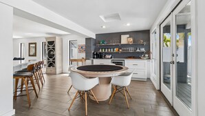A modern kitchen with a round dining table, white chairs, and a built-in oven.