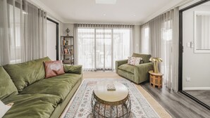 Una sala de estar con un sofá verde, una mesa de centro redonda y un tapete estampado.