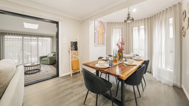 Un comedor moderno con una mesa de madera, sillas negras y una lámpara de araña.