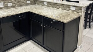 A kitchen with dark cabinets, granite countertops, and a tiled floor. - Katy Brick Haven (Katy)