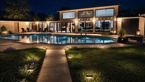 A modern two-story building with a swimming pool, outdoor seating, and a well-lit entrance.