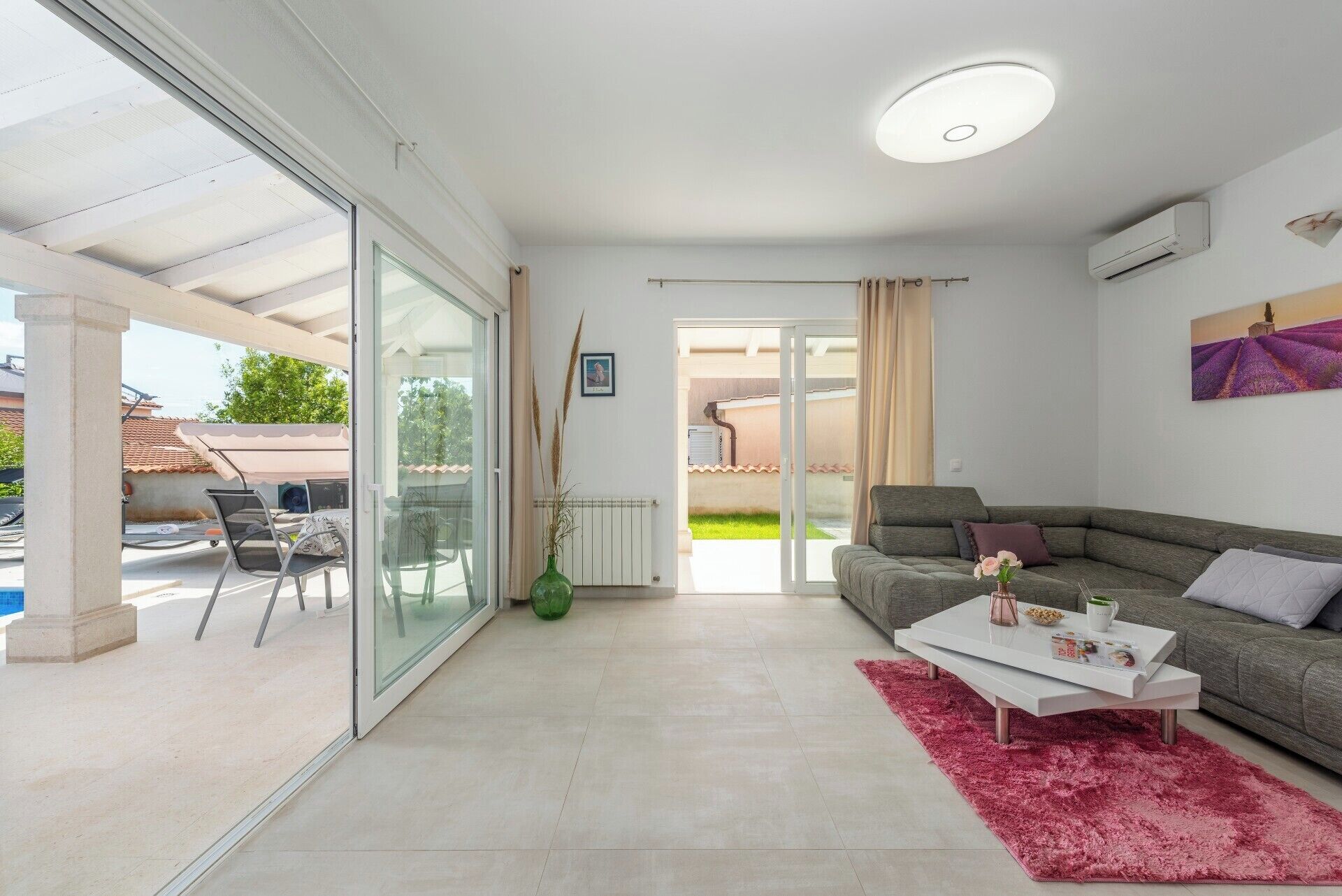 Un salon moderne avec un canapé, une table basse et une porte vitrée donnant sur un espace extérieur.
