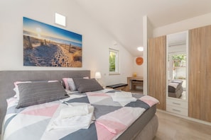 A bedroom with a bed, a desk, a chair, a mirror, and a painting of a beach scene. - Villa Delijamo by Istrabook (Poreč)
