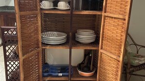 Un mueble de madera con varios estantes, que contiene utensilios de cocina y cajas de almacenamiento.