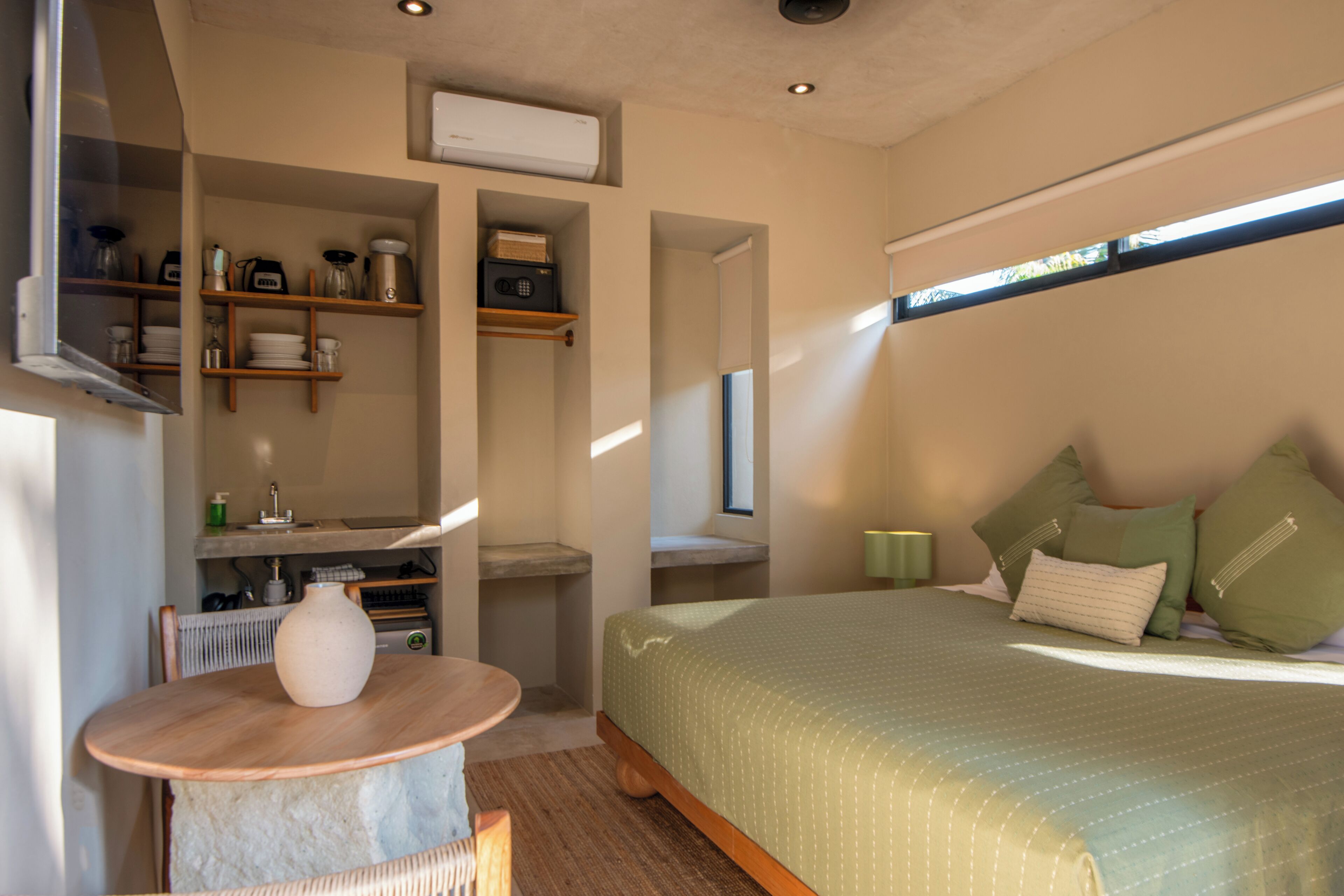 A bedroom with a bed, a table, and shelves with various items.