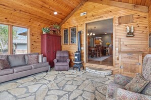 A cozy cabin interior with a stone floor, a sofa, a chair, a red cabinet, and a wood-paneled exterior. - Historic Harbor - Timeless, Location & 2 Slips! (Lake Ozark)