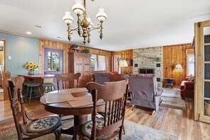 A wooden-paneled room with a dining table, chairs, a sofa, and a fireplace. - Historic Harbor - Timeless, Location & 2 Slips! (Lake Ozark)