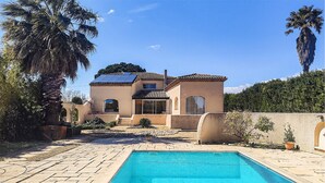 Ein Haus mit Schwimmbad, Terrasse und Garten.