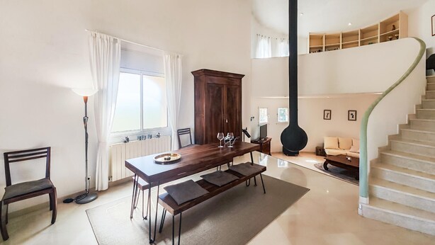 Ein Essbereich mit Holztisch, Bänken, einem Schrank, einer Treppe und einer Heizung.