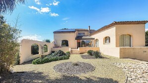 Eine mediterrane Villa mit Innenhof, Solaranlage und einem Kiesweg.