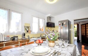 Eine moderne Küche mit einem Esstisch für zwei Personen, einem Kühlschrank und einem Fernseher über dem Herd.