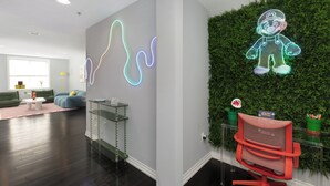 Een modern interieur met een neonlicht muur, een groene wand met een plant, een rode stoel en een glazen tafel.
