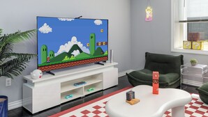 Een woonkamer met een televisie, een witte salontafel, een rood-wit geruit tapijt, een groene bank en een raam met jaloezieën.