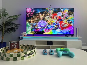 Un televisor de pantalla plana montado en la pared, mostrando el juego Mario Kart Deluxe.