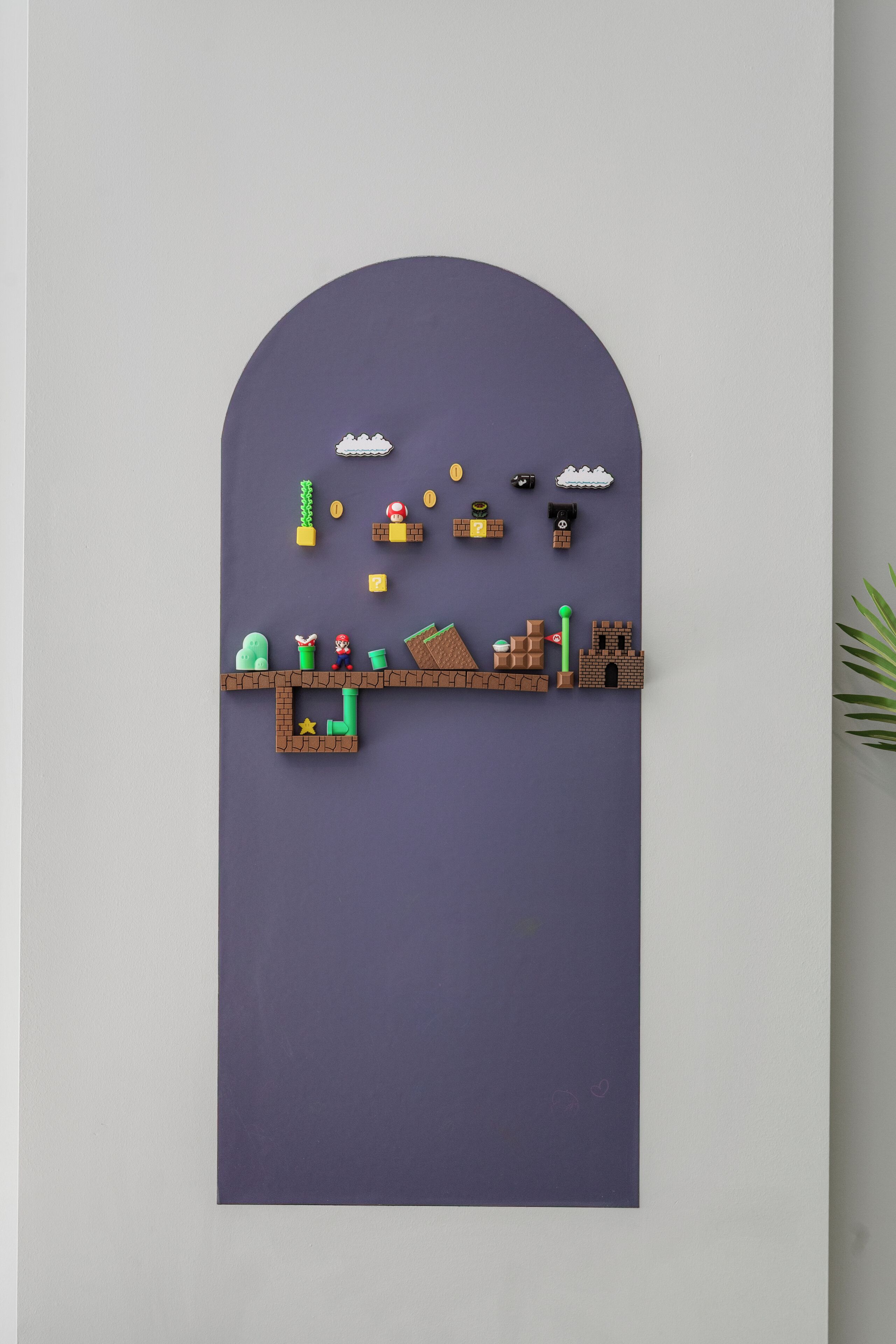 Uma obra de arte suspensa na parede, com superfície plana e parte superior arredondada, apresentando um design simples com diversas formas e ícones.