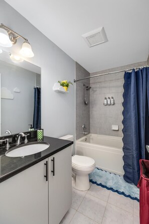 A modern bathroom with a vanity, sink, toilet, shower, and bathtub.