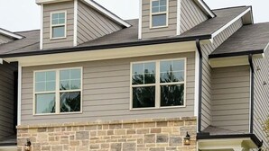A two-story house with a stone facade, a garage, and a small porch. - Luxury Gated Townhome For Full World Cup Stay w/2 Car Garage + Safe & Private (Atlanta)