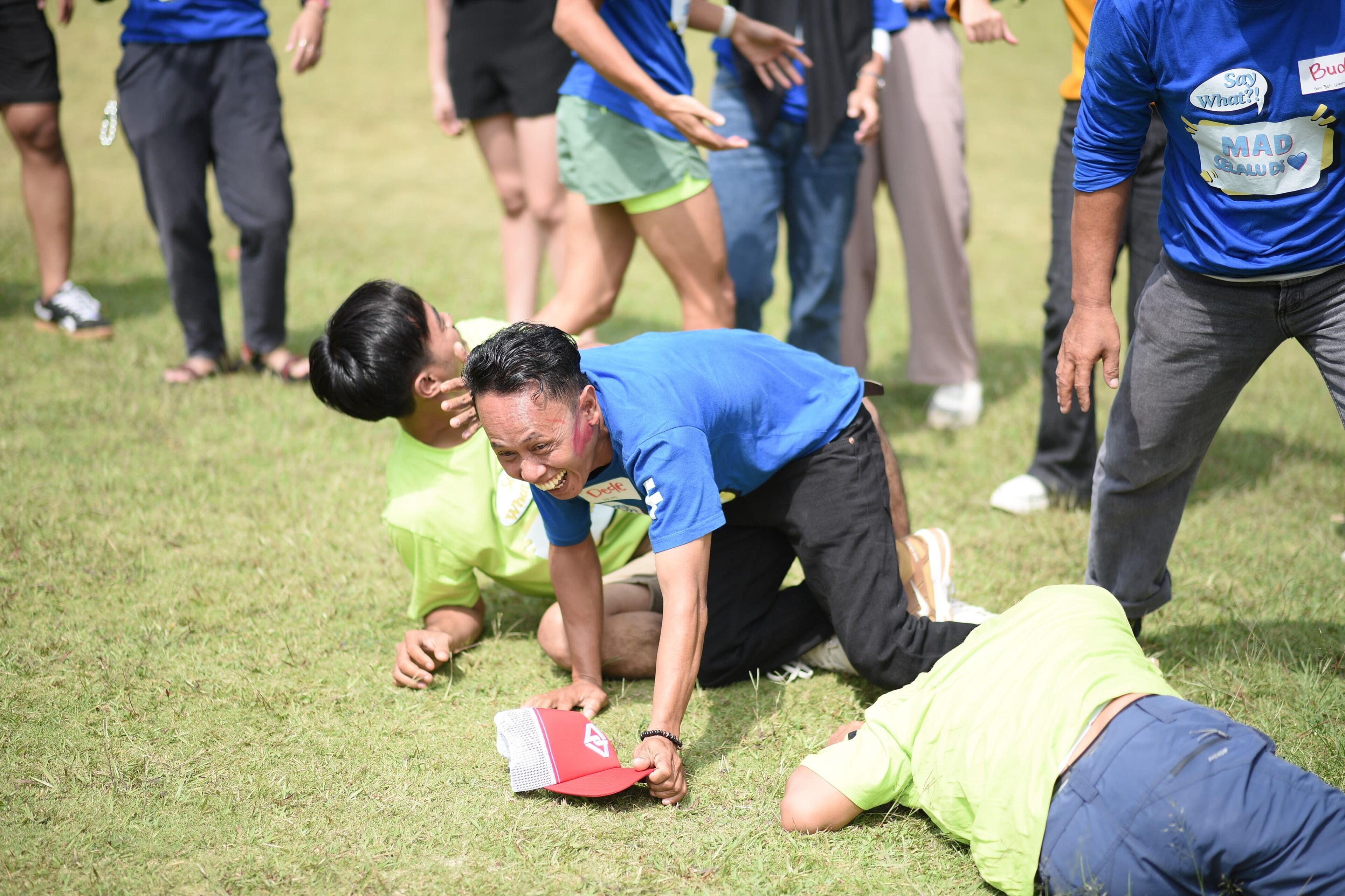 A group of people on a grassy field, some in athletic wear, with one person lying on the ground.
