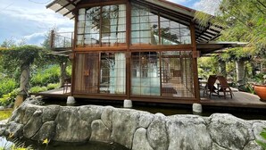 A traditional Japanese-style building with large glass windows, a wooden deck, and a koi pond. - Vila Air Natural Resort (Parongpong)