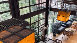 A modern interior with large windows, a seating area with tables and chairs, and a hanging light fixture. - Vila Air Natural Resort (Parongpong)