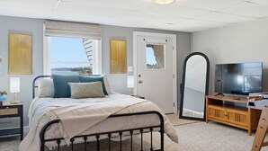 Ein Schlafzimmer mit einem Bett, einem Fernseher, einem Holzschrank, einem Spiegel und einem Fenster mit Blick.