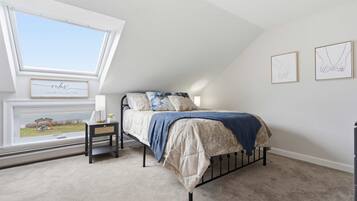 A bedroom with a bed, a nightstand, a window, and two wall art pieces.