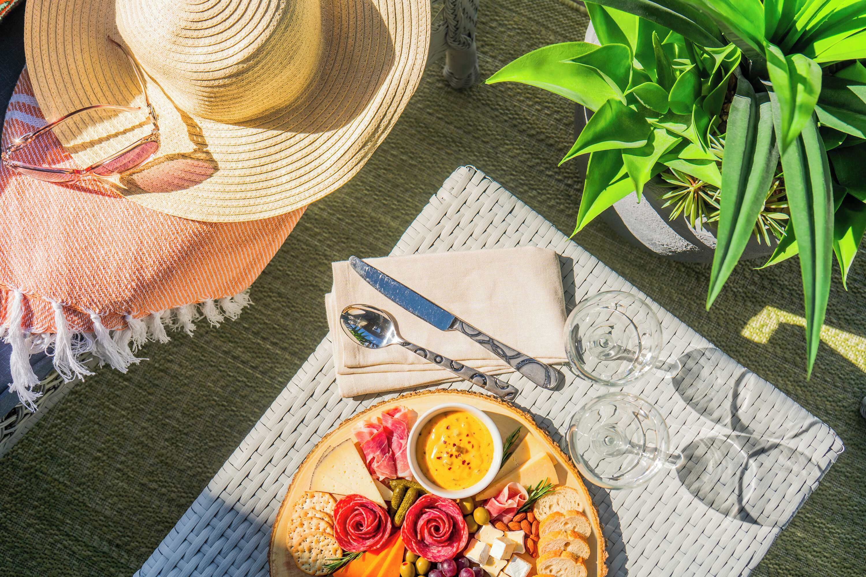 Une table avec une assiette de nourriture, un chapeau, des lunettes de soleil et une cuillère.