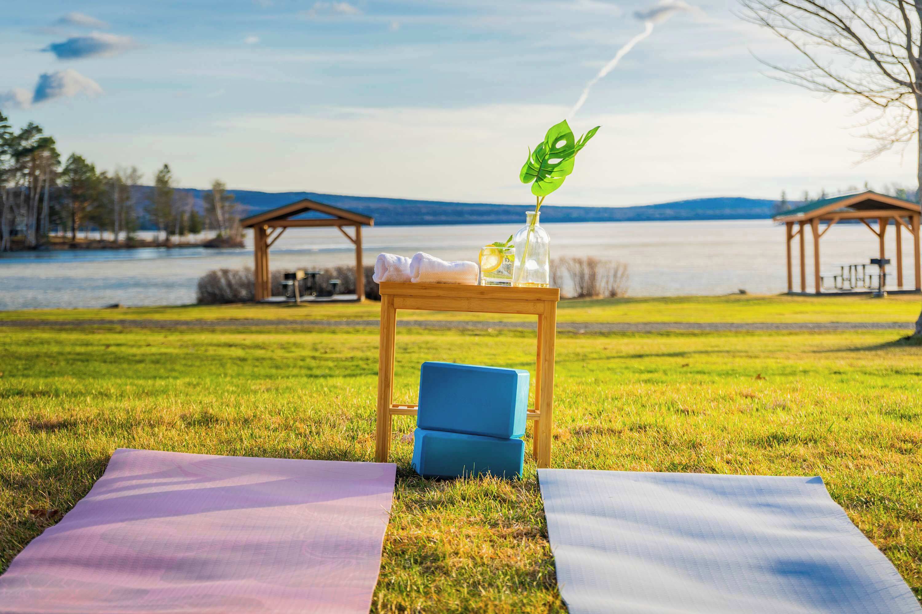 A grassy area with a wooden table, a blue chair, and a yoga mat.