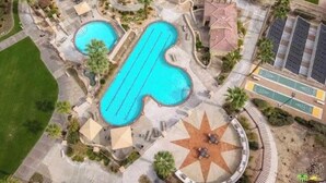 Vista aérea de un resort con varias piscinas, un patio solar en forma de estrella y un estacionamiento.
