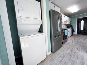A kitchen with a stainless steel refrigerator, a built-in oven, and a washing machine. - Sea Palm Breeze (Fort Walton Beach)
