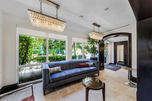 Eine moderne Lobby mit einem blauen Sofa, großen Fenstern und einer Kristallleuchtre.'