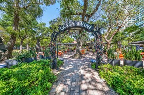 An outdoor area with a sign reading 'GLASS & VINE,' surrounded by trees and potted plants. - One Bedroom Coconut Grove Apartment with Large Patio & Free Parking (Miami)