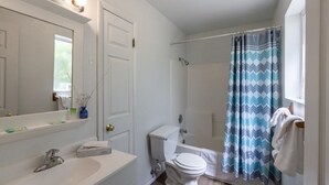 A bathroom with a white sink, mirror, toilet, and shower curtain. - Clean, Modern & Close to Everything Double Room At Silversage Inn (Moab)