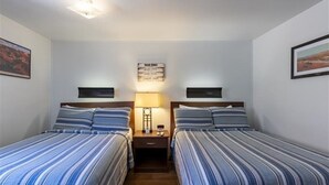 A room with two beds, each with striped bedding, a nightstand with a lamp, and a wall-mounted sign. - Clean, Modern & Close to Everything Double Room At Silversage Inn (Moab)