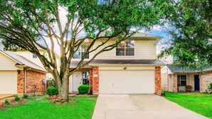 A two-story house with a garage, a tree in the front yard, and a well-maintained lawn. - Empress Modern Haven (Houston)