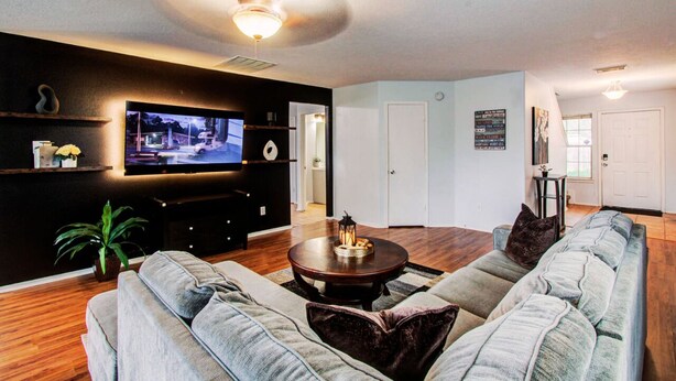 A living room with a flat-screen TV, a round coffee table, and a sofa. - Empress Modern Haven (Houston)