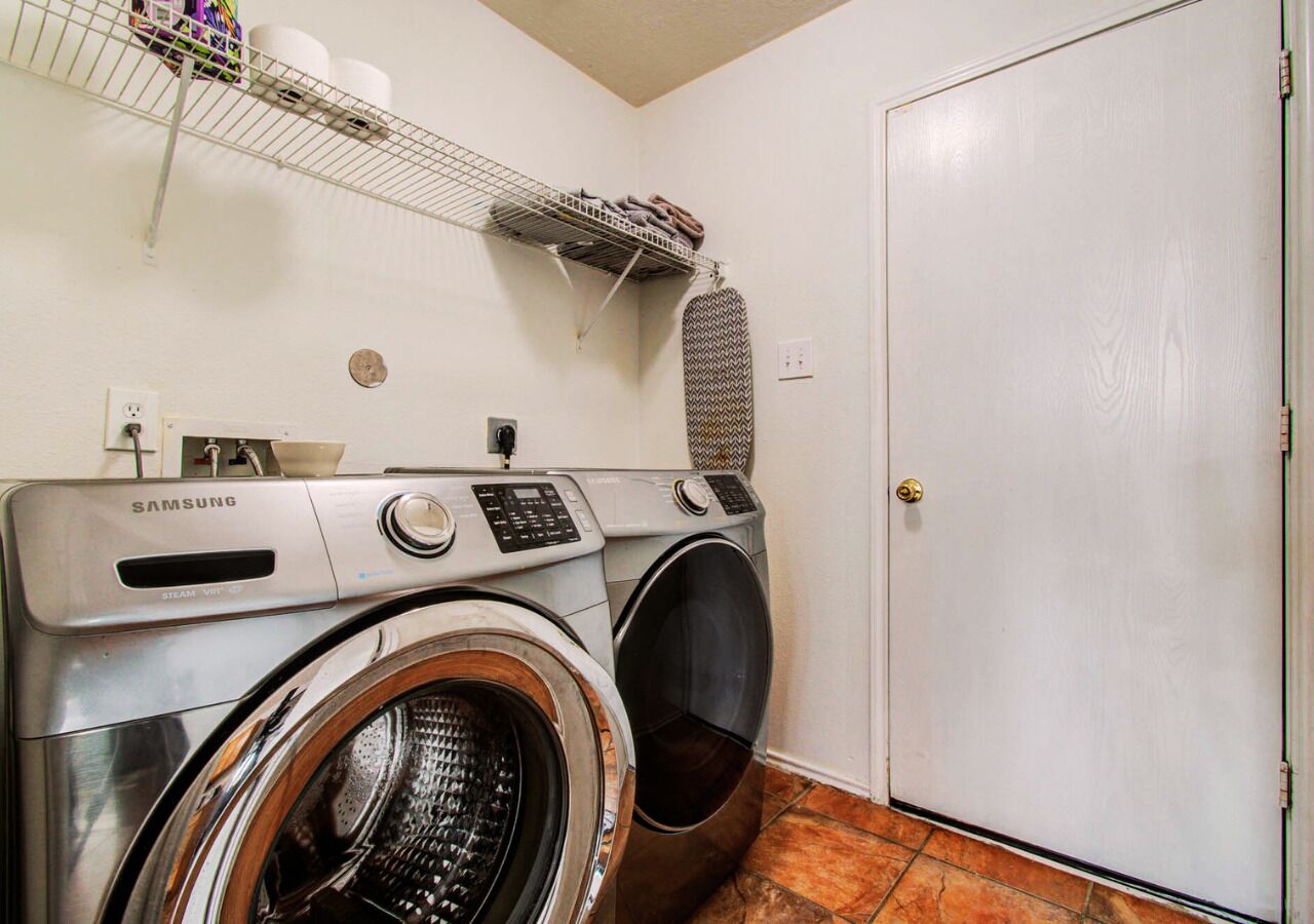 A laundry area with a Samsung washer and dryer, a shelf with towels, and a door.