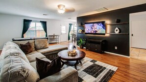 A modern living room with a sofa, coffee table, TV, and a fireplace. - Empress Modern Haven (Houston)