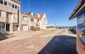 Una calle costera con edificios, cielo despejado y vista al mar.