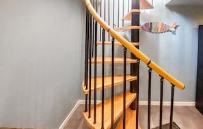 Una escalera de madera con barandales negros y una decoración de pez en la pared.