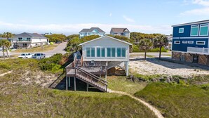A beachfront house with a deck, a staircase leading to the beach, and a view of the ocean. - Reelaxing: Oceanfront Home in Yaupon Beach, Oak Island, Perfect for 9 guests! (Oak Island)