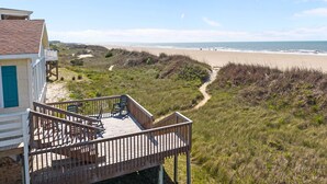 A beach house with a deck, a path leading to the beach, and a view of the ocean. - Reelaxing: Oceanfront Home in Yaupon Beach, Oak Island, Perfect for 9 guests! (Oak Island)