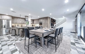 Una cocina moderna con una isla central, electrodomésticos de acero inoxidable y un comedor con sillas.