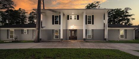 A two-story house with a front porch, a driveway, and a well-maintained lawn.