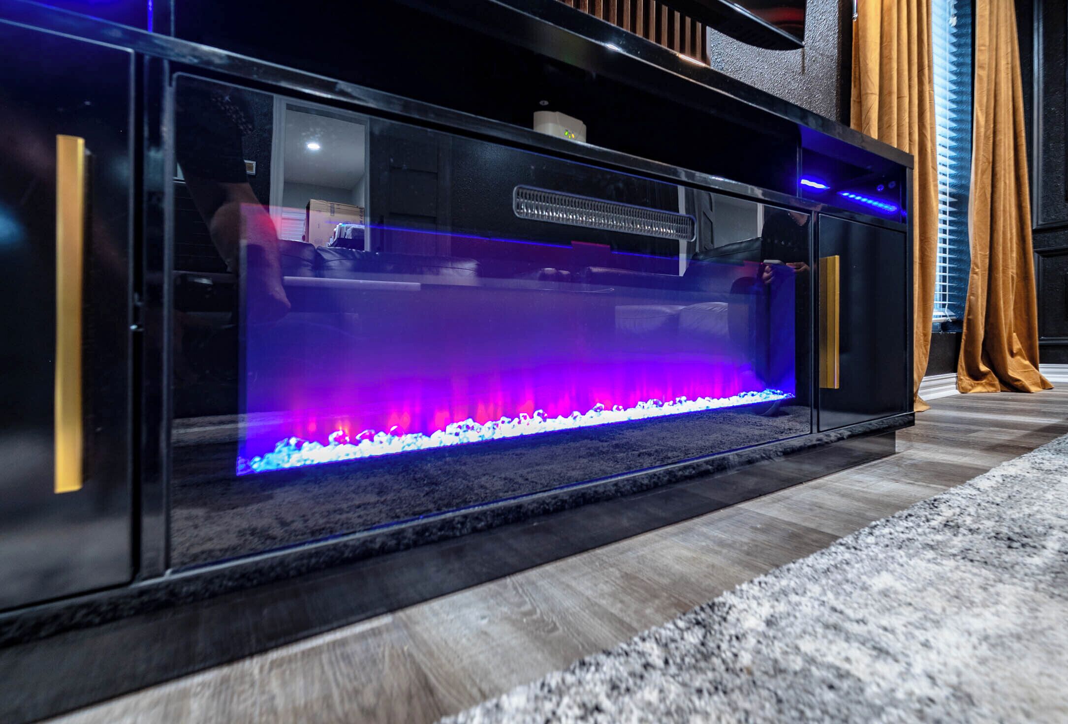 Een modern aquarium met een ingebouwd lichtsysteem, geplaatst op een houten vloer met een donker vloerkleed.
